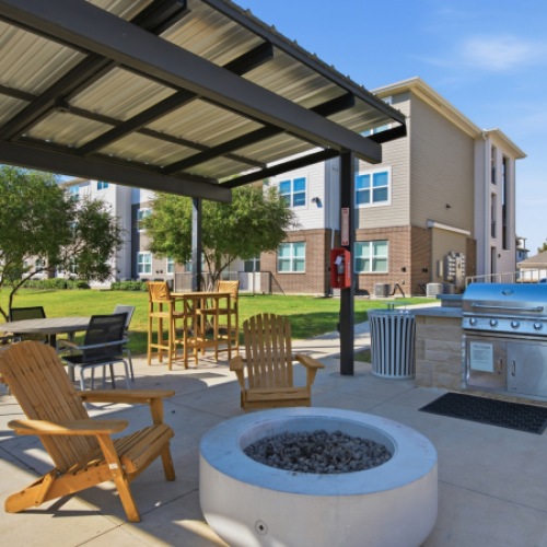 Outdoor grilling and dining area with picnic tables and a pergola at Latitude Magnolia