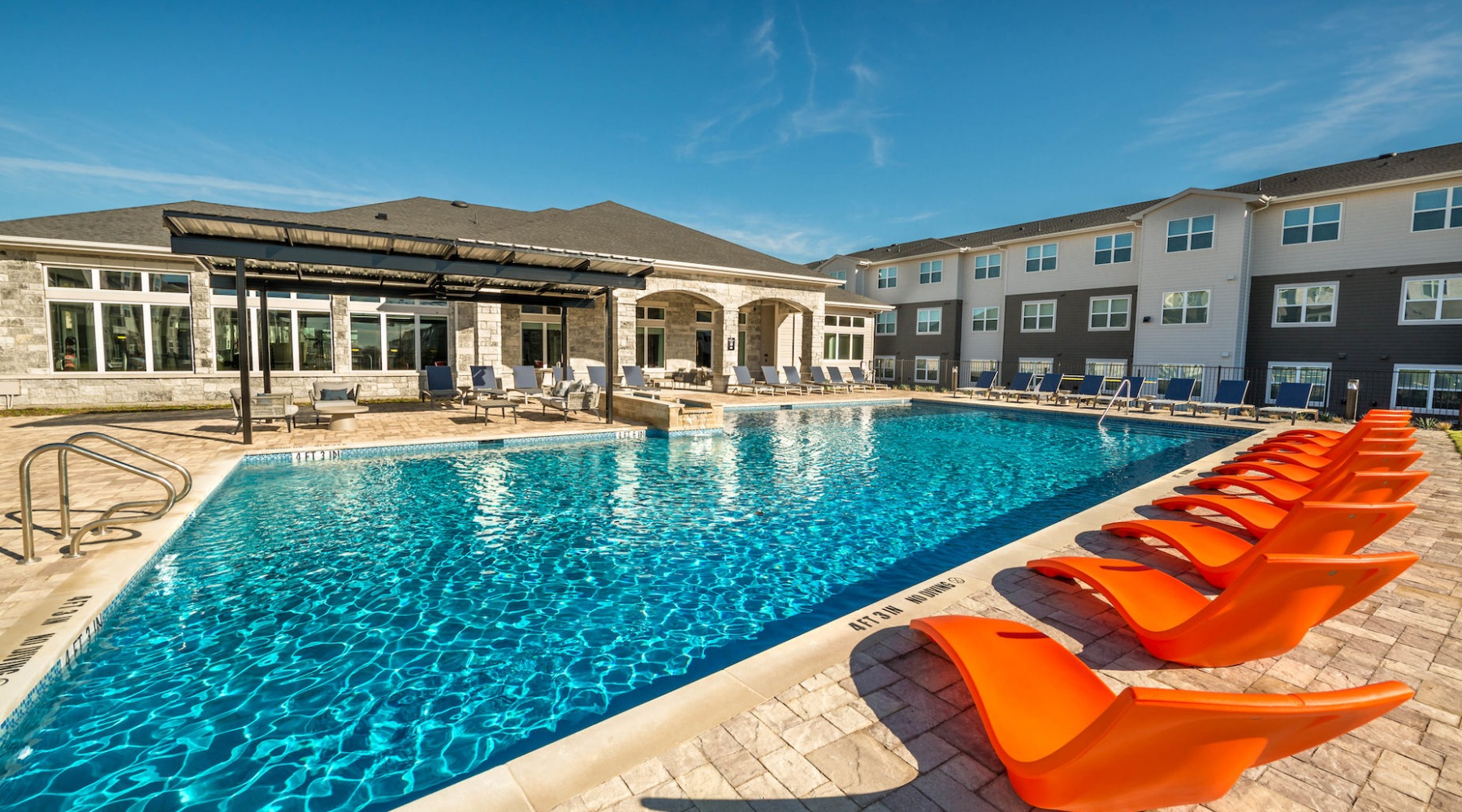 Pool area at our apartments for rent in Aubrey, TX, featuring beach chairs, umbrellas, and a clubhouse. Pool area at our apartments for rent in Aubrey, TX, featuring beach chairs, umbrellas, and a clubhouse.