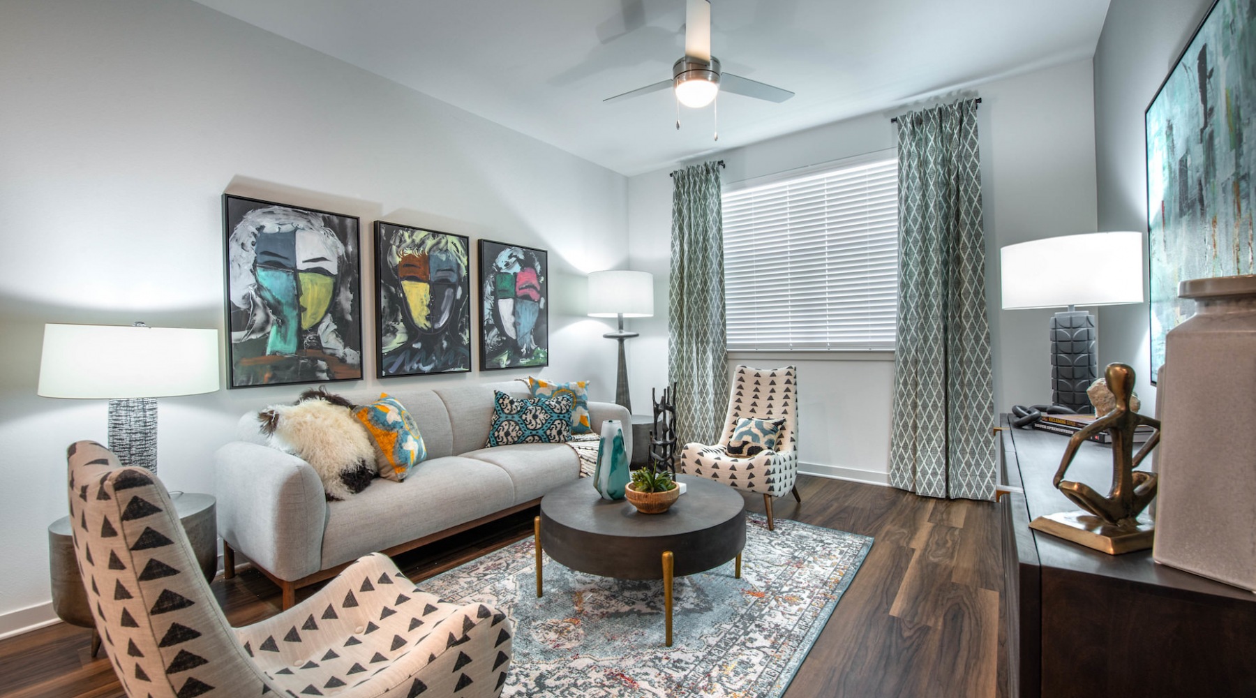 Model living room at our apartments for rent in Aubrey, TX, featuring wood grain floor paneling and windows with curtains. Model living room at our apartments for rent in Aubrey, TX, featuring wood grain floor paneling and windows with curtains.